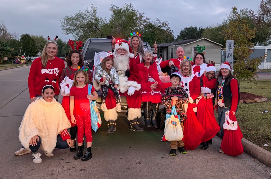 Group of volunteers posing with Santa and Mrs. Claus before giving out toys